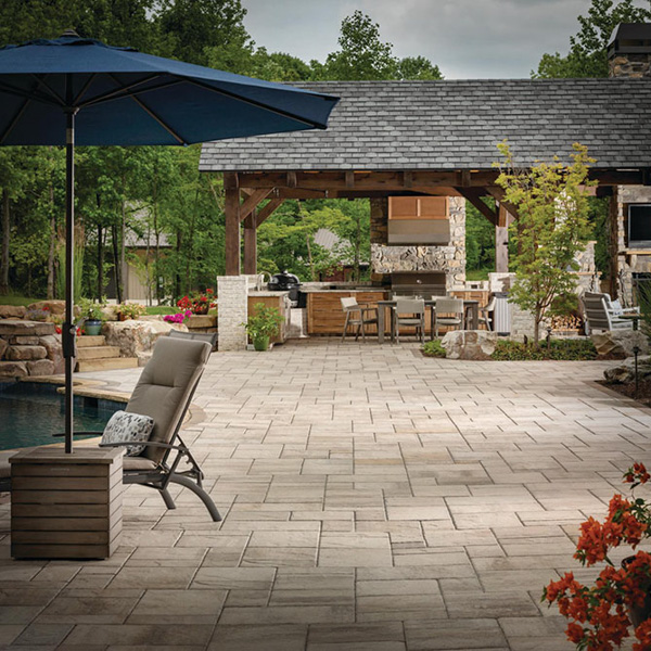 beautiful paver patio with a kitchen in the background